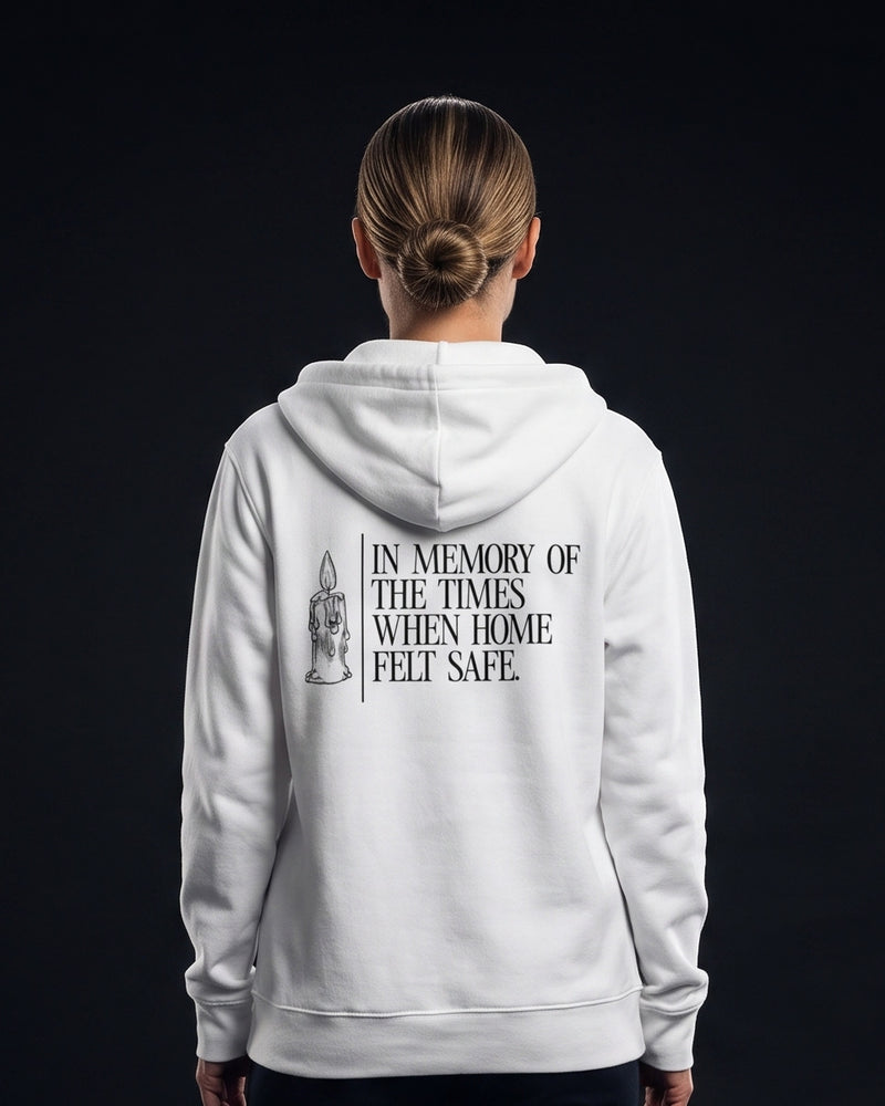 Frau von hinten in weissem Zip-Hoodie mit Kerzen-Illustration und dem Schriftzug 'In memory of the times when home felt safe.'