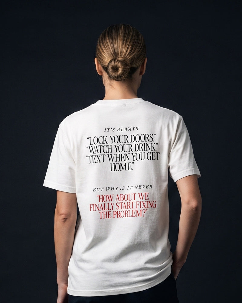 Frau trägt das WORN OPINIONS T-Shirt „It's alwasy this and never that“ in Weiß von hinten, Rückenprint It's always lock your doors, watch your drink, text when you get home, but why is it never how about we finally start fixing the problem