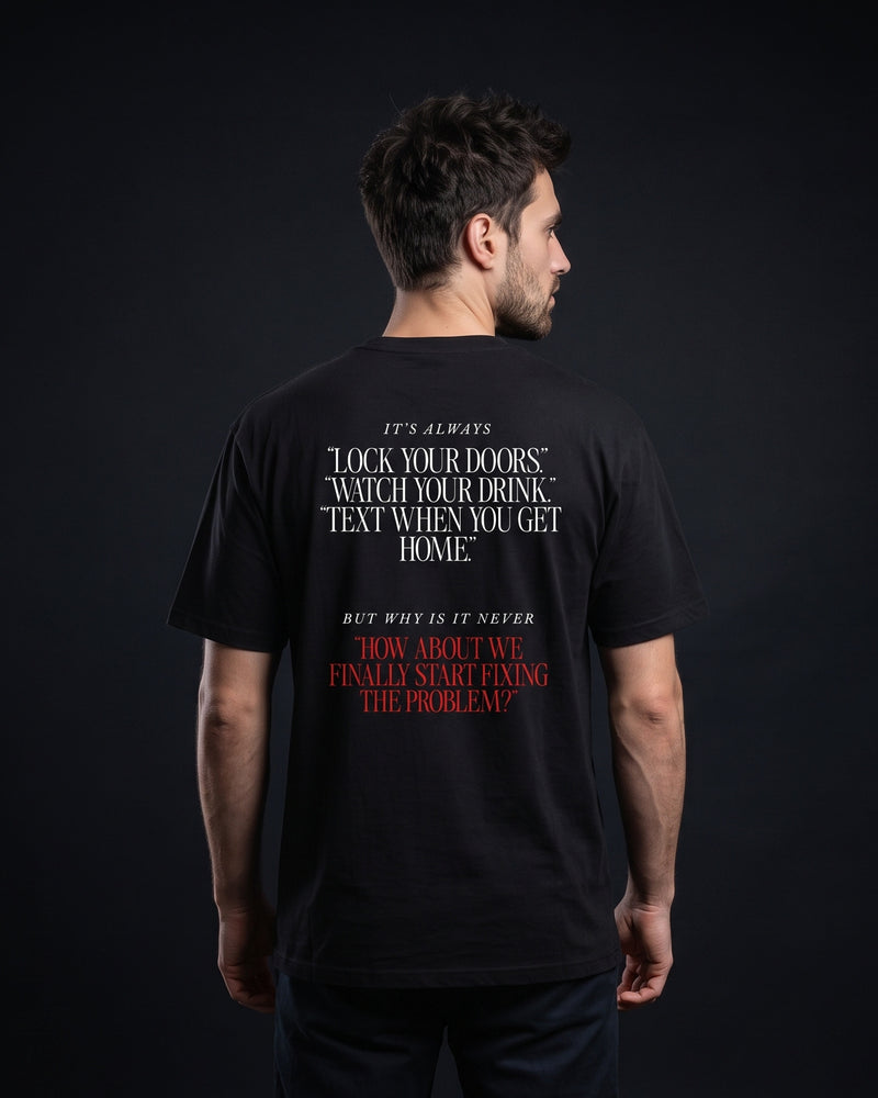 Mann trägt das WORN OPINIONS T-Shirt „It's alwasy this and never that“ in Schwarz von hinten, Rückenprint It's always lock your doors, watch your drink, text when you get home, but why is it never how about we finally start fixing the problem