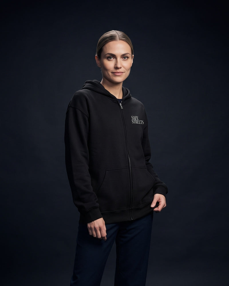 Frau in schwarzem Zip-Hoodie mit kleinem Brustprint 'Safe Streets'