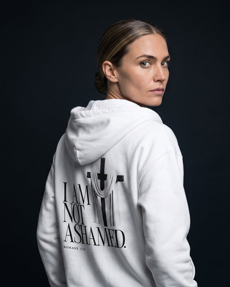Frau in weissem Zip-Hoodie mit Rueckenprint "I am not ashamed.", Bibelstelle Romans 1:16 und Kreuz-mit-Tuch-Grafik