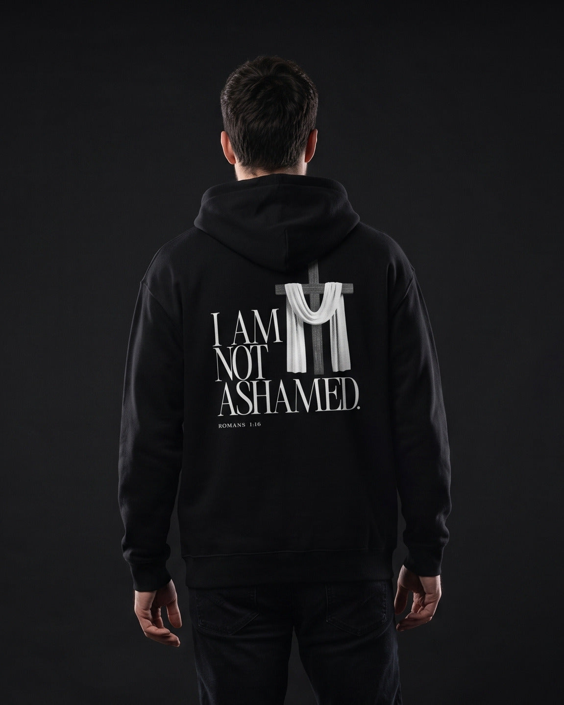 Mann in schwarzem Zip-Hoodie mit Rueckenprint "I am not ashamed.", Bibelstelle Romans 1:16 und Kreuz-mit-Tuch-Grafik