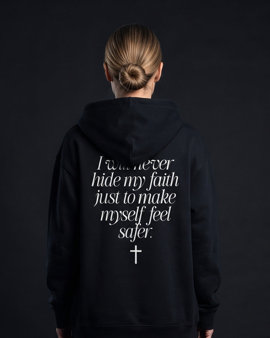 Frau in schwarzer Zip-Hoodie mit Rueckenprint 'I will never hide my faith just to make myself feel safer.' und einem Kreuz-Symbol darunter