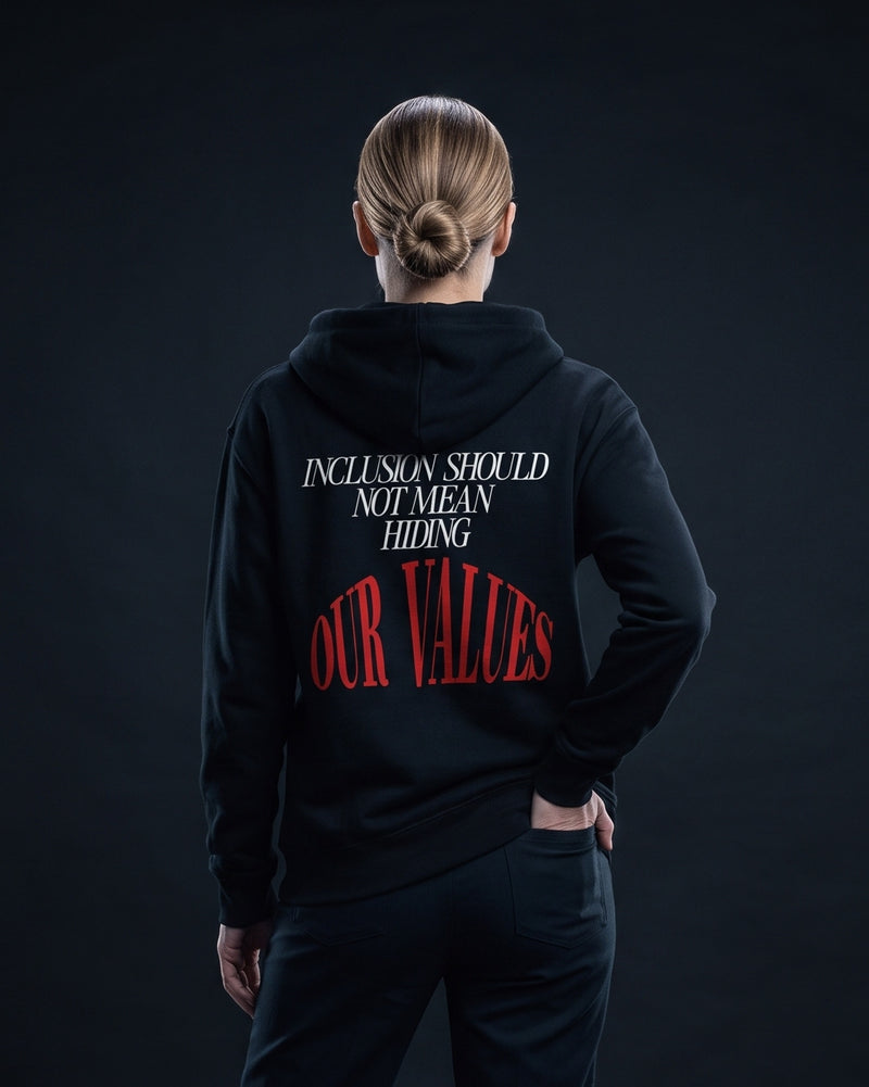 Frau traegt die WORN OPINIONS Kapuzenjacke Inclusion should not mean hiding our values in Schwarz von hinten, Rueckenprint Inclusion should not mean hiding, unten rot OUR VALUES