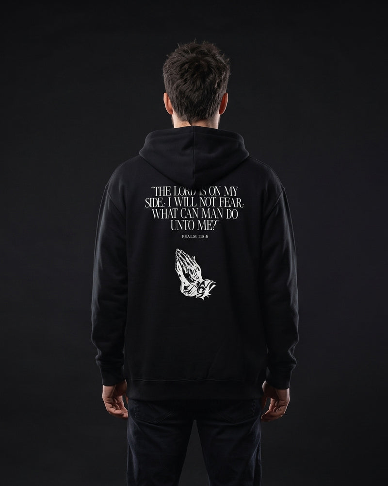 Mann traegt schwarzen Zip-Hoodie mit Rueckendruck "The Lord is on my side; I will not fear; what can man do unto me?", Psalm 118:6, und Grafik betender Haende