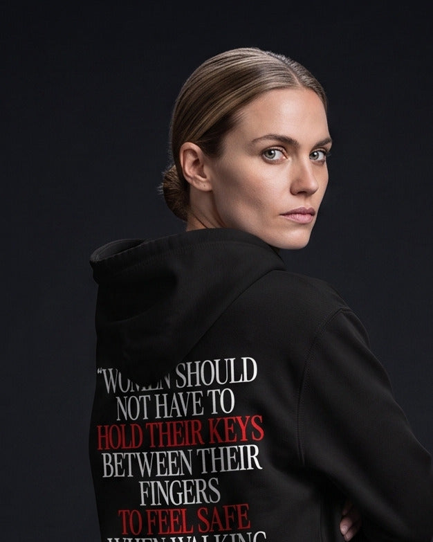Frau trägt den WORN OPINIONS Hoodie Women should not have to hold their keys between their fingers in Schwarz von hinten, Rückenprint „Women should not have to hold their keys between their fingers to feel safe when walking home alone!“ – The safety of women is a fundamental right!